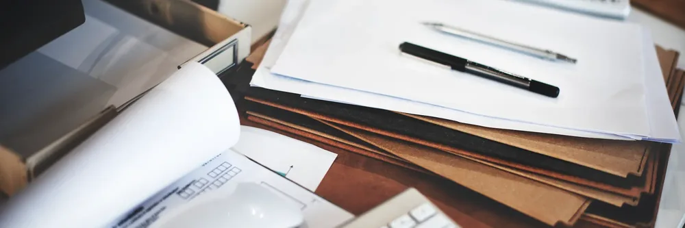 Bureau d'une office manager externalisée : documents, dossiers et stylo posés sur un plan de travail