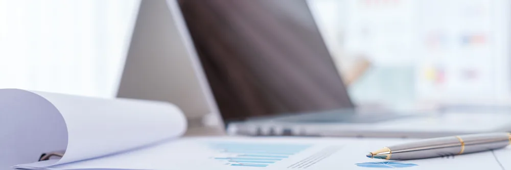 Documents chiffrés et ordinateur portable pour évaluer le budget d'une office manager externalisée